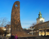 Na pierwszym planie pomnik przedstawiający najważniejsze dzieła literackie wieszcza ukraińskiego Tarasa Szewczenki, a na drugim planie wieża kościoła katolickiego - katedry lwowskiej na wycieczce jednodniowej z Bieszczad zimą.
