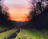 Przejazd kolejowy w Bezmiechowej po zachodzie słońca z pięknym pomarańczowym niebem. Od 2014 roku po torach, które prowadzą z Zagórza w stronę Ustrzyk Dolnych jeżdżą drezyny rowerowe, które w 2015 roku zostały Najlepszym Produktem Turystycznym Podkarpacia i Polski.