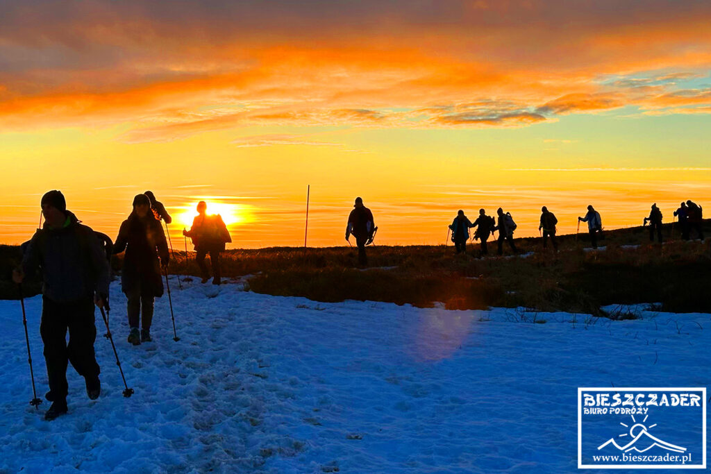 Turyści wędrujący o zachodzie słońca na rakietach śnieżnych zimą po Połoninie Caryńskiej - Bieszczadzki Park Narodowy.